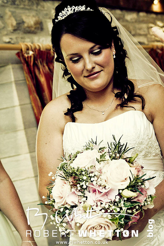 Wedding of Jo and Ben Christie at Kingston Country Courtyard, Swanage Jo admiring her bouquette - Dorset Wedding Photographer Robert Whetton