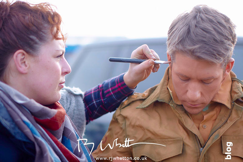Rosie Lee adds final make-up to orange army man Rosie Lee adds final make-up to orange army man - Production Photography Dorset